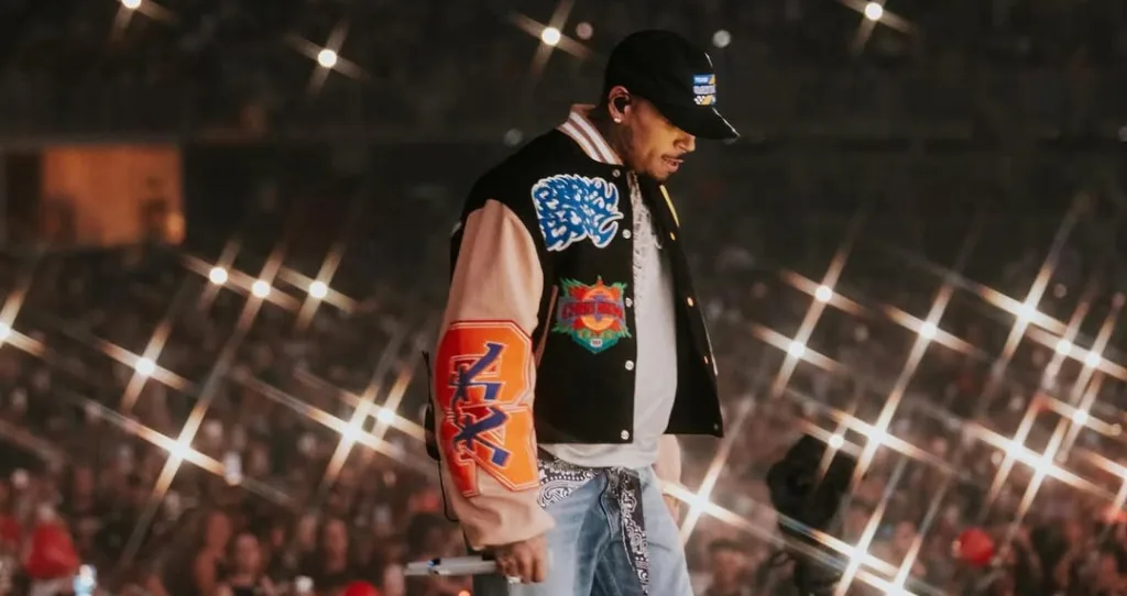 Chris Brown on stage in a varsity jacket under concert lights